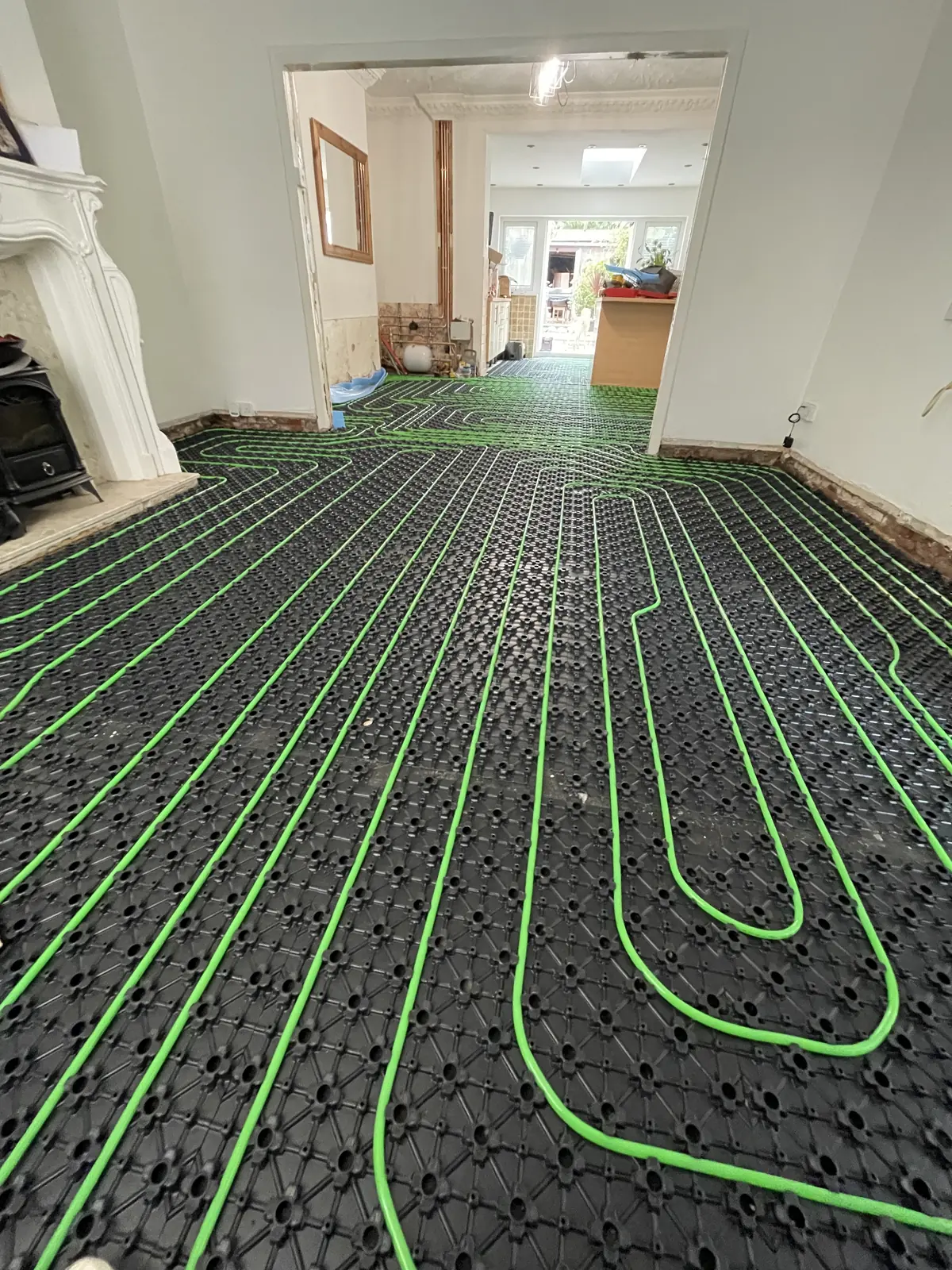 White underfloor heating pipe clipped across green overlay panels